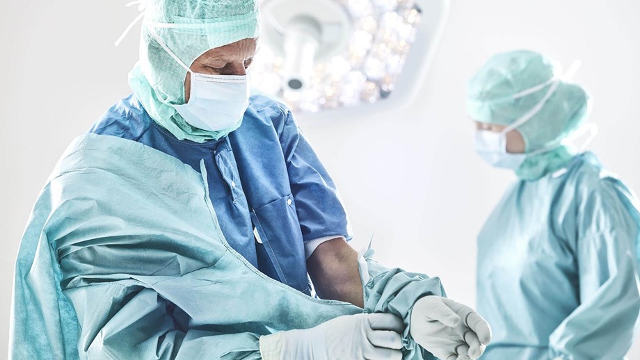 Chirurg die een operatiejas aantrekt voor een operatie