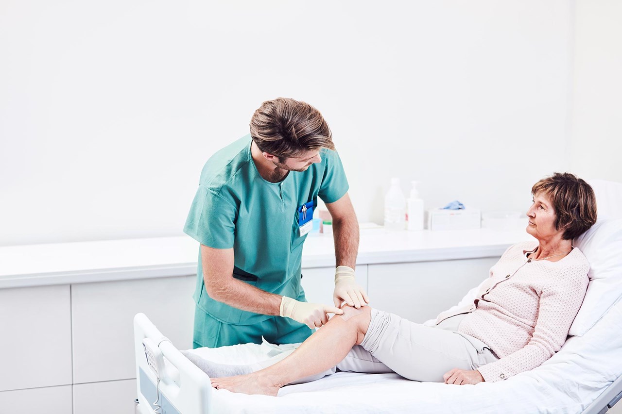 Male nurse tending to an elderly female patient